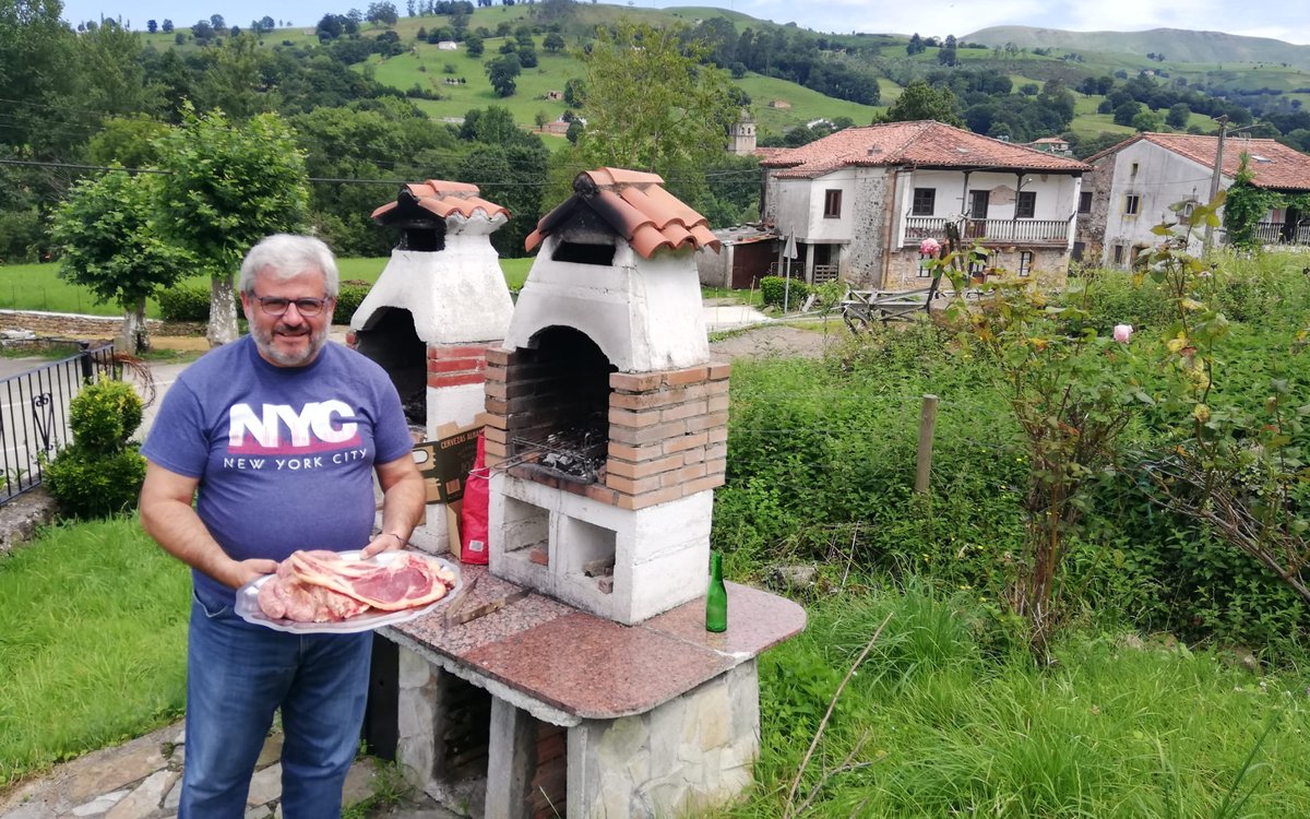 Barbacoa de obra prefabricada instalada en un jardín del norte de España, con una bandeja de chuletón lista para la parrilla