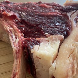 Chuletón de vaca con hueso y veta de grasa sobre tabla de madera