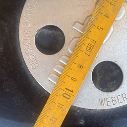 Metro de carpintero midiendo la tapa de una barbacoa Weber
