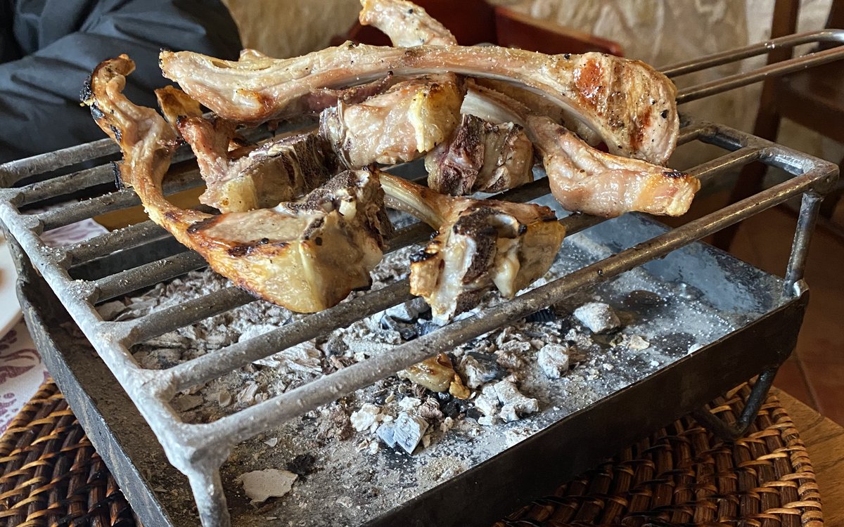 Parrilla portátil de hierro con costillas de cordero sobre las brasas en un restaurante de la Ribera del Duero